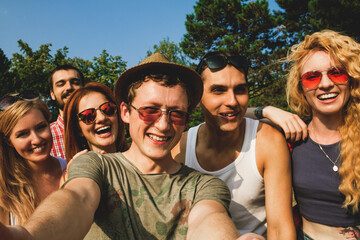 Friends having fun together in the park. Taking a selfie