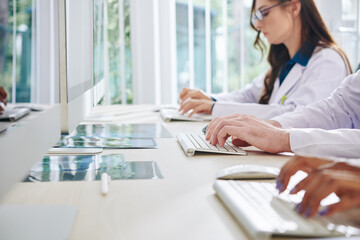 Medical laboratory researchers working on computers, entering data and analyzing statistics and results of medical tests