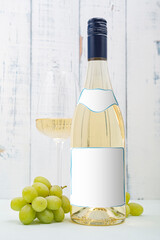 Bottle of white wine with label. Glass of wine and grape.