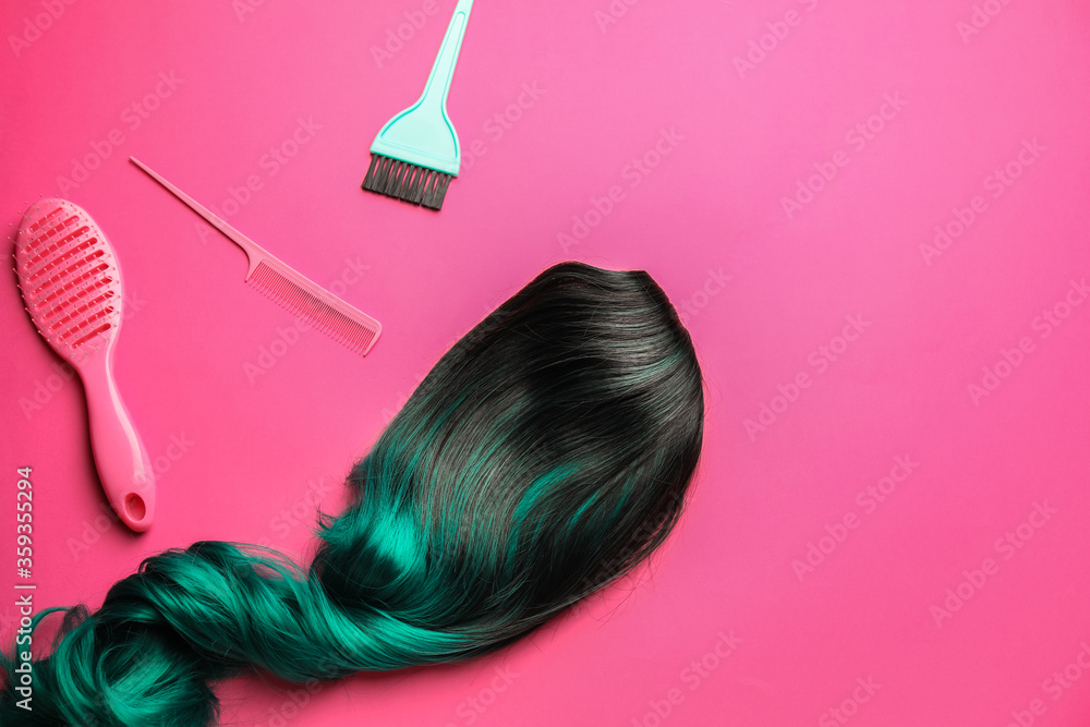 Unusual wig, brushes and comb on color background