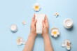 © Pixel-Shot - Hands of young woman with cream and flowers on color background