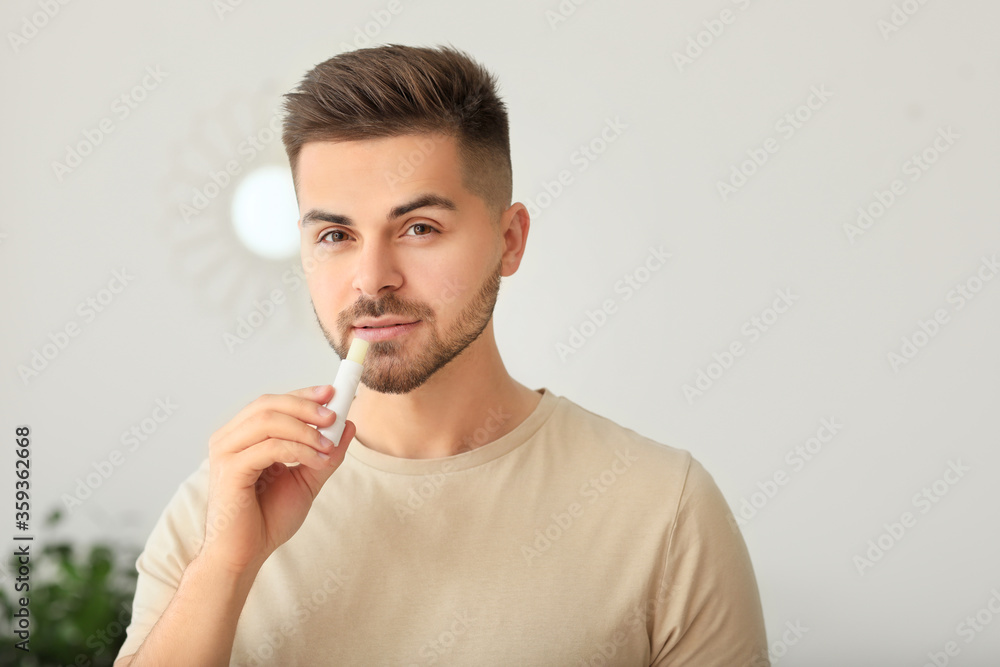 Handsome young man with lip balm at home