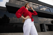 Fashion Model In Red Blouse Posing On City Street Wearing Sunglasses