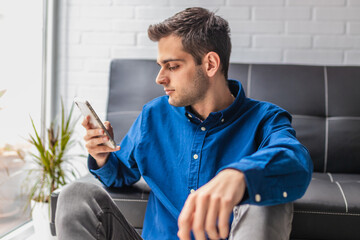 Wall Mural - portrait of young man with mobile phone at home