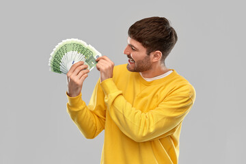 Wall Mural - people concept - smiling young man in yellow sweatshirt with money over grey background