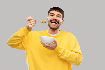 Sticker - food and people concept - happy smiling young man eating cereals over grey background