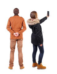 Canvas Print - Back view of couple in winter jacket photographed on a mobile phone in winter jacket.