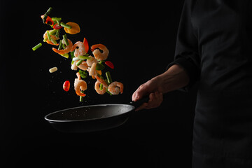 Wall Mural - Cooking shrimp seafood with vegetables on a black background, freezing in motion