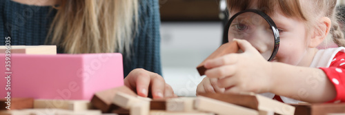 Fotografía Daughter looks through magnifier at wooden bar