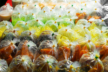 Wall Mural - Colored desserts in plastic bags at a street food market in Asia. Unusual Asian food.