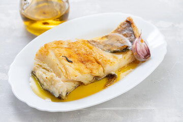 Sticker - fried cod fish with garlic and olive oil on white dish