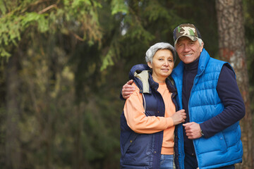 Wall Mural - waist up portrait of active senior couple embracing and looking at camera while enjoying hike in for