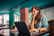 © bnenin - Portrait of a positive woman using laptop in restaurant, piece of cake on the table.