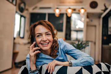 Poster - Close-up portrait of a happy businesswoman talking on the phone at home.