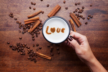 A rustic mug with coffee cream. Food art creative concept image, drawing with cinnamon powder over wooden background.