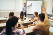 © Mediteraneo - Smiling teacher standing in front of students and showing something on white board in classroom