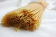 Long uncooked spaghetti on a white cotton tablecloth. Close-up of a pile of pasta. Selective focus
