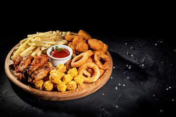 Wall Mural - Fried chicken, nuggets , fries and tomato sauce on dark background