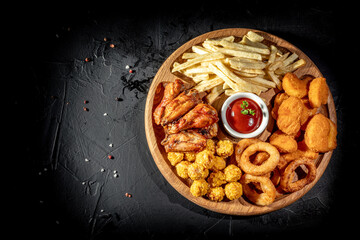 Wall Mural - Fried chicken, nuggets, fries and tomato sauce on dark background