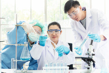 Wall Mural - team work asian woman and man scientists analyzing virus data and evaluating microscope