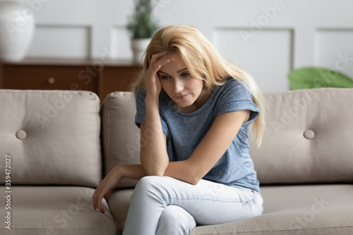 Upset young woman sitting on couch looks unhappy, thinking about problems life troubles, break up and personal failure. Teenager suffers for unrequited first love, unsure girl, low self-esteem concept