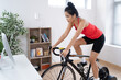 © torwaiphoto - Asian woman cyclist. She is exercising in the house.By cycling on the trainer
