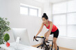 © torwaiphoto - Asian woman cyclist. She is exercising in the house.By cycling on the trainer