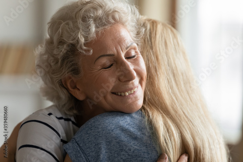 Sincere elderly mother glad to see grown up daughter visited mom hugs her enjoy moment express love and mental connection close up. Family ties, parents and their offspring, gratitude for care concept