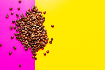 aromatic Roasted coffee beans pile pink and yellow background. top view