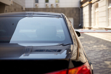 Back window of black car parked on the street in summer sunny day, rear view. Mock-up for sticker or decals