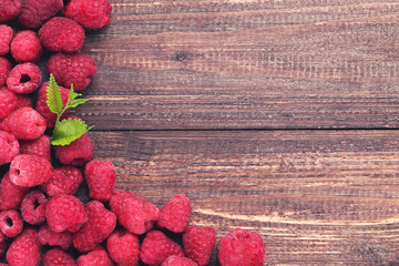 Poster - Sweet raspberries with green leafs on brown wooden table