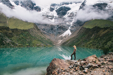 Female tourist in active wear admiring beauty scenery of amazing nature during hiking trek in Salkantay.Young woman traveller enjoying exciting mountains covered white clouds and recreation of trip