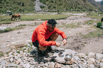 Wall Mural - Latino American male tourist in active wear getting fire with matches for cooking on metallic burner during trekking tour for exploring wild natural environment in National Park, concept of adventures