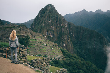 Wall Mural - Rear view of young woman enjoying amazing scenery of high hills and mountains during trekking wanderlust.Professional female tourist admiring beautiful nature during hiking trip in Salkantay