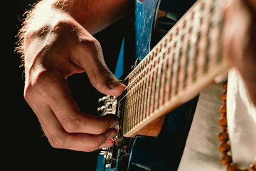 Wall Mural - Close up of male hand playing electric guitar in the dark