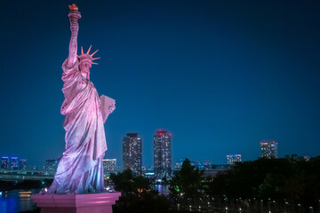 Wall Mural - Japan. Statue of liberty in Tokyo. Statue of liberty on Odaiba island. Statue of liberty close-up on the background of the evening city. Tokyo Attractions. Sculptures of the Japanese capital.