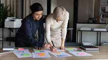 Multiracial Businesswomen Work On Project Statistics, Prepare Financial Report Use Post-it Memo Notepapers Making Notes Do Sales Overview, Colleagues Analysing Charts Data, Teamwork Brainstorm Concept