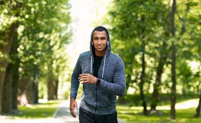 Smiling black athlete training for marathon at green park in summer