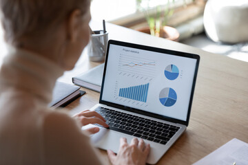 charts, graphs, analysis sales information on laptop screen view over financier shoulder, visual rep