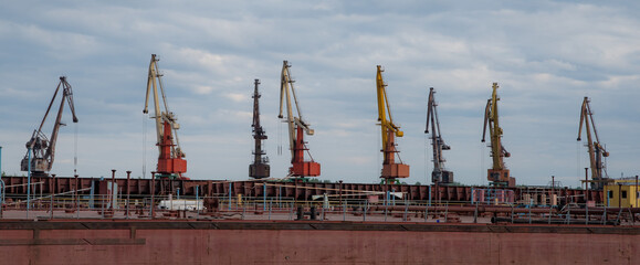 Shipbuilding plant. Crane operation at the shipbuilding, commercial, sea, river, port. Loading, unloading of goods, bulk materials by cranes of the river port (dock).