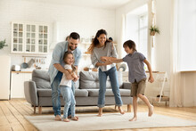 Happy Family Playing Funny Game Having Fun Together With Little Son And Daughter In Modern Living Room. Young Dad And Mother With Adorable Cute Children Doing Exercises, Enjoying Weekend At Home.