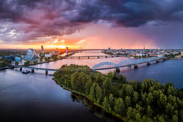 Aerial view of iconic Riga city downtown in dramatic sunset. Modern architecture in rainy weather with storm clouds in warm colors. 