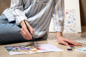 Poster - Woman painting flowers with watercolor on floor, closeup