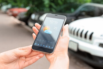 Wall Mural - woman using weather forecast app on smartphone outdoors, closeup
