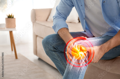 Fotomural Man suffering from knee pain at home, closeup