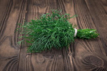 A bunch of fresh dill on a wooden table.