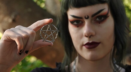 Wall Mural - Close up of a silver pentacle held up by a teen Wiccan. Note: Focus is on pentacle.