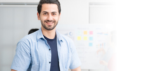 Confidence team leader. Young man owner startup business and looking at camera with smile while his colleagues working in the background