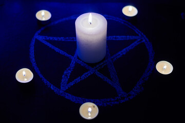 Pentagram and burning candles. The magical ritual of Satanism, invocation of spirits, spiritualistic sessions.