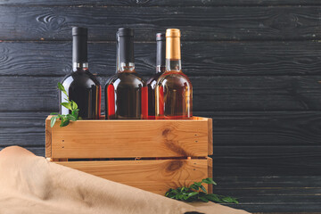 Box with bottles of wine on dark wooden background